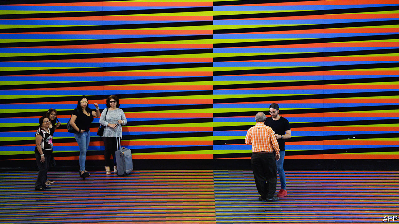 Travellers walking over Carlos Cruz-Diez's floor of colourful stripes at the airport that serves Caracas