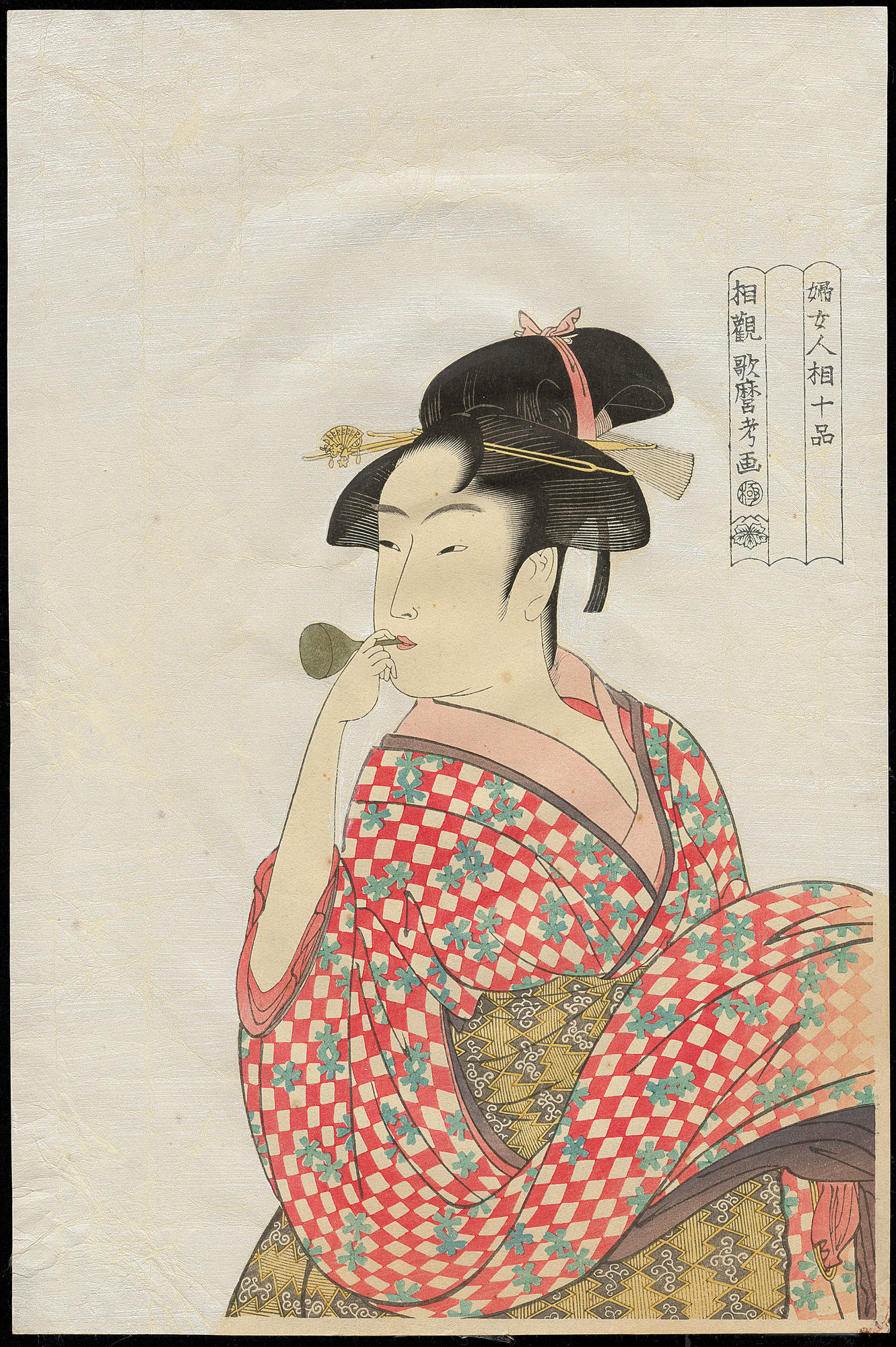 Utamaro's young woman, shown from the chest up in a kimono patterned with red checks and cherry blossoms, blowing into a glass toy against a pale, shimmering mica ground